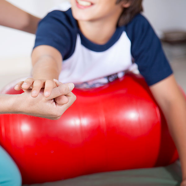 Physiotherapeutin behandelt Jungen auf Pezziball
